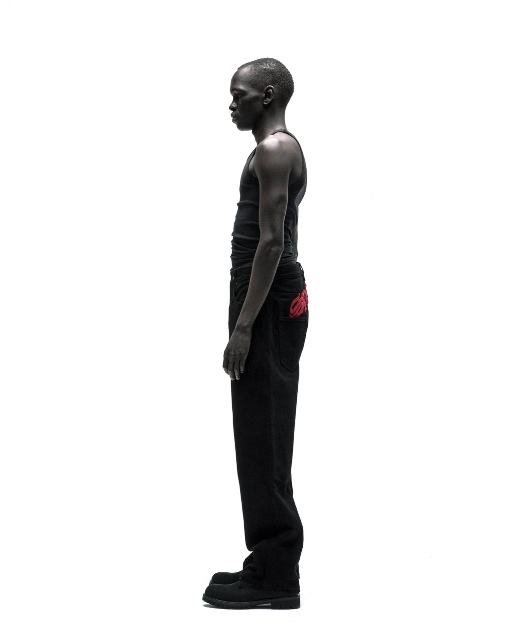 Man in black OXY JEANs with red embroidered text above back pockets, classic straight leg fit.