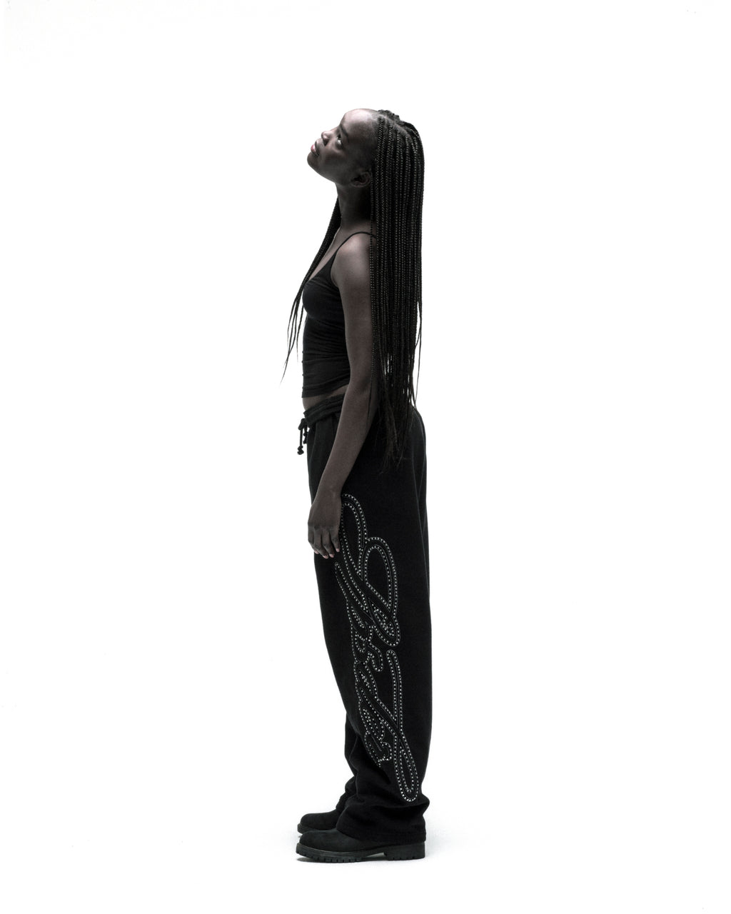 Black 100% cotton wide-leg sweatpants with rhinestone script down the leg, worn by a model.