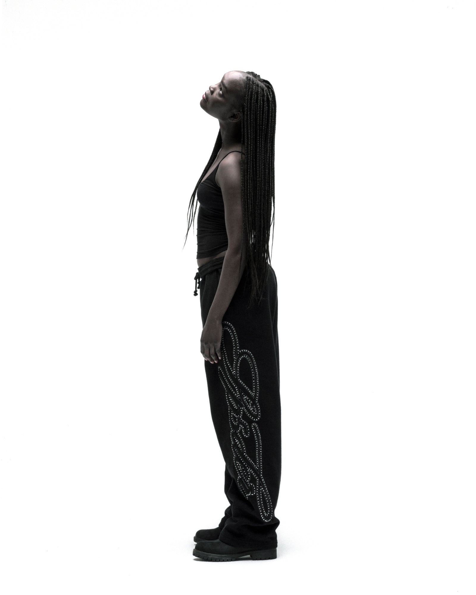 Black 100% cotton wide-leg sweatpants with rhinestone script down the leg, worn by a model.