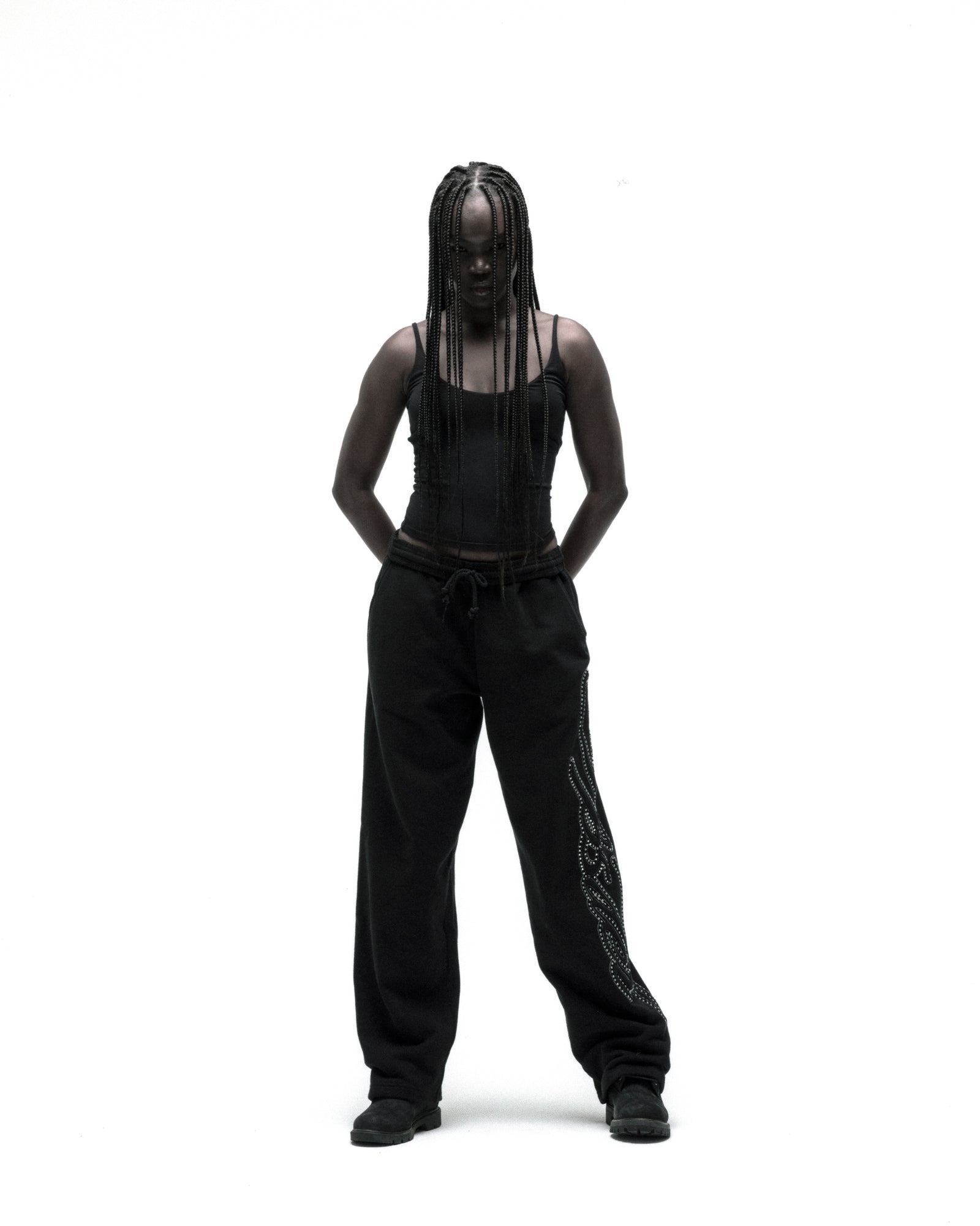 Black cotton fleece wide-leg sweatpants with rhinestone script down the leg, worn by a model.