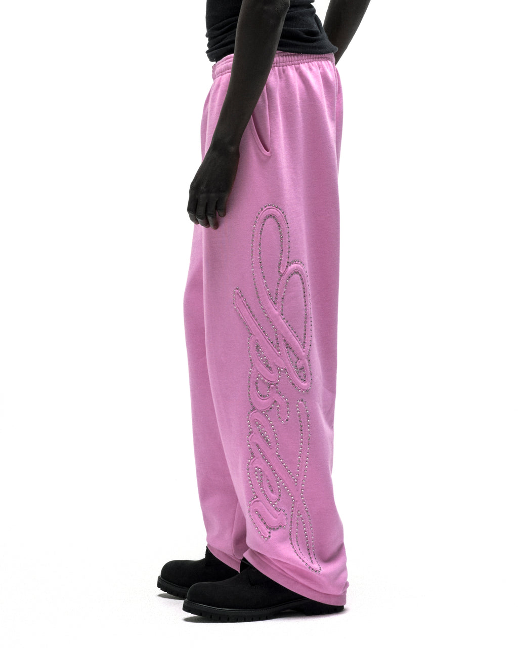 Pink wide-leg cotton fleece sweatpants with rhinestone script down the leg.