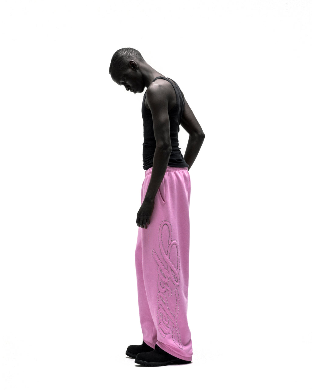 Model in pink wide-leg cotton sweatpants with rhinestone script design down the leg.