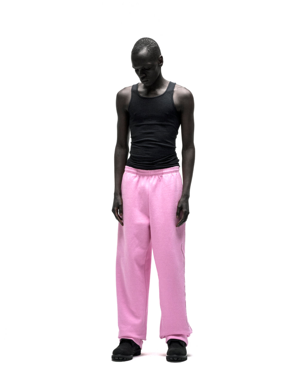 Model wears pink wide-leg cotton fleece sweatpants with rhinestone script down the leg.