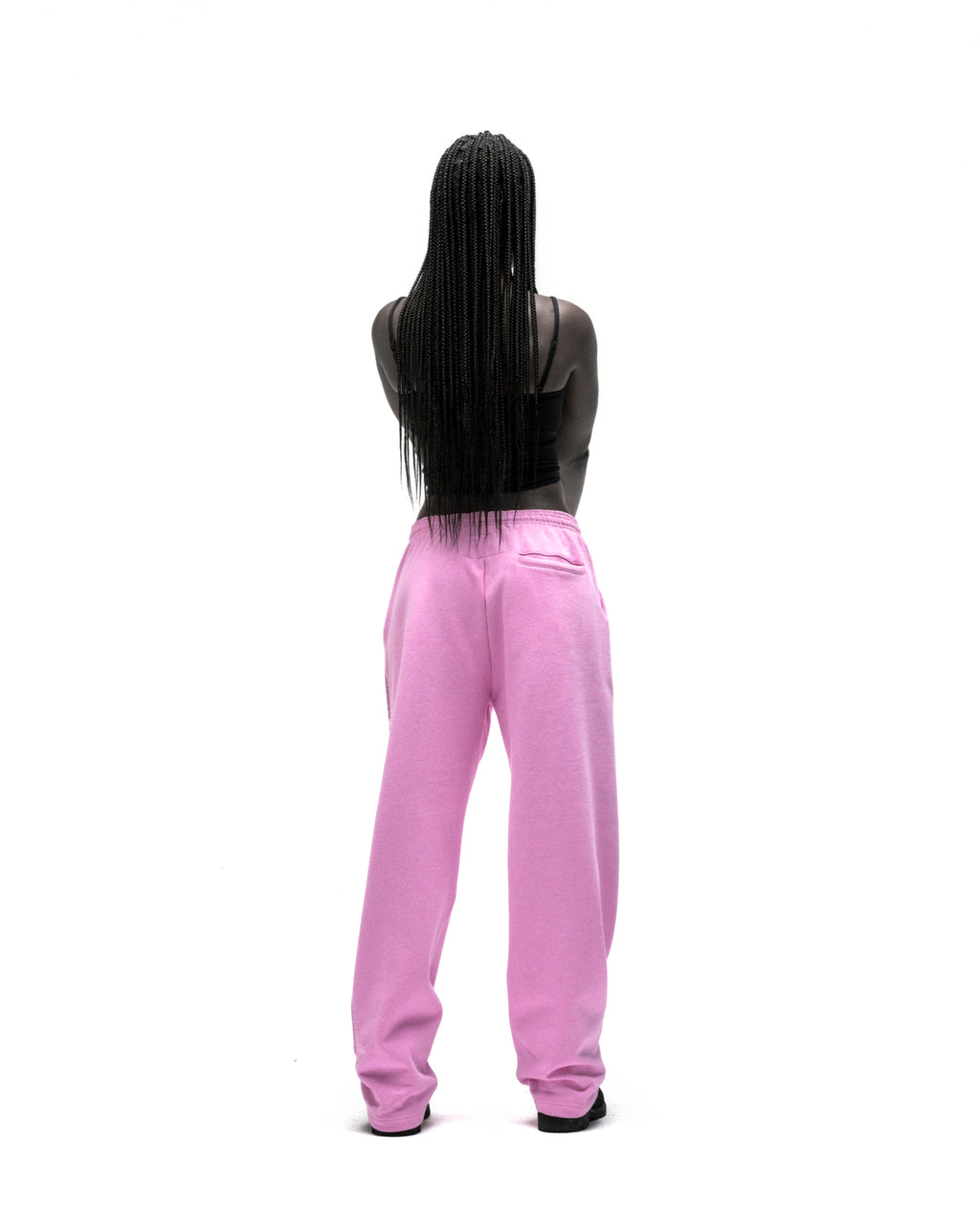 Back view of a person wearing pink wide-leg sweatpants with a rhinestone script design.