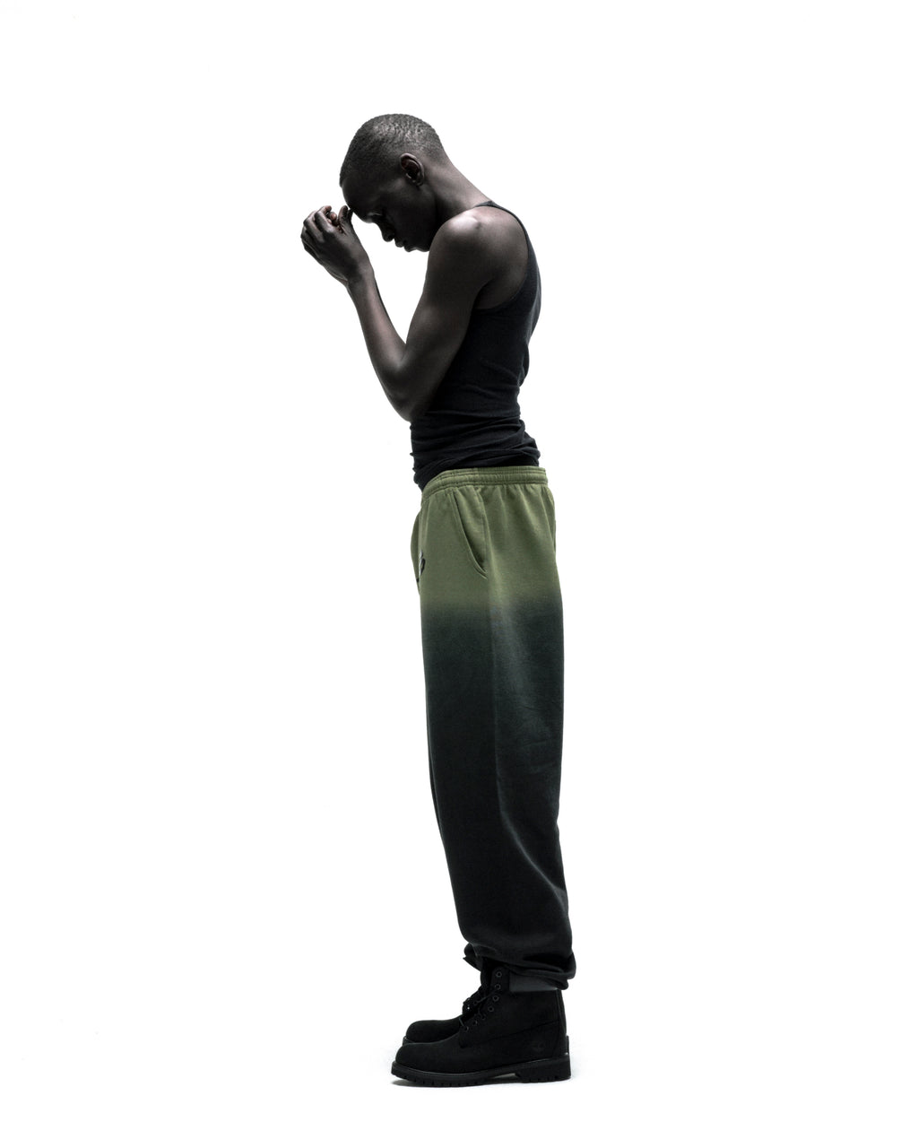 Man in OG WEB OMBRE SWEATPANT: green to black ombre, 100% cotton fleece, 'SP5DER' text.
