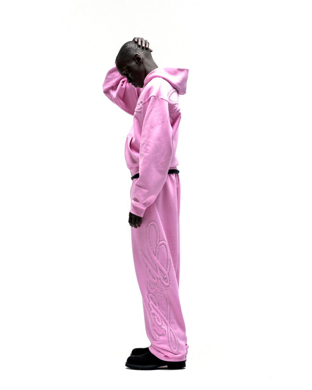 Pink rhinestone script zip hoodie and matching sweatpants on a model.
