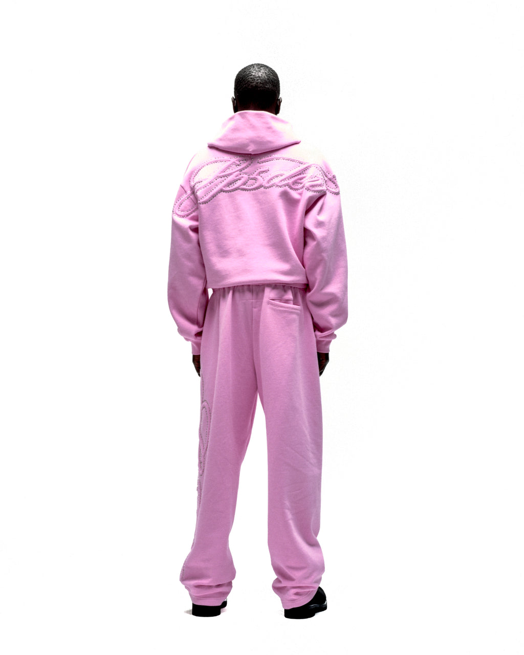 Pink fleece zip hoodie and sweatpants set with rhinestone script text on back and leg.