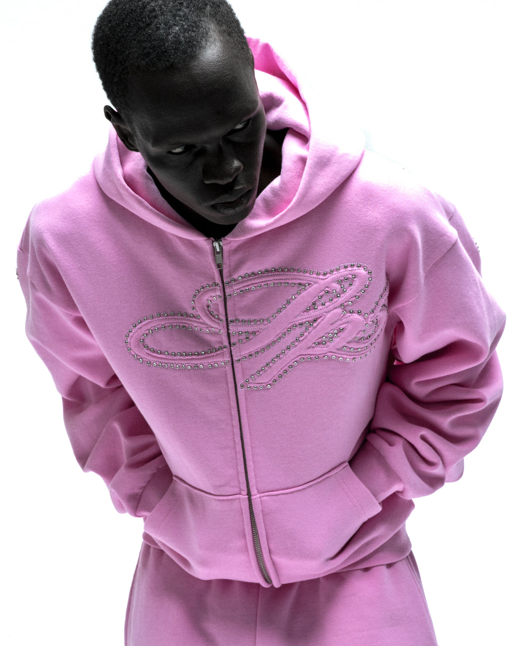 Pink cotton fleece zip hoodie with rhinestone script design on the chest, kangaroo pocket, and ribbed cuffs.