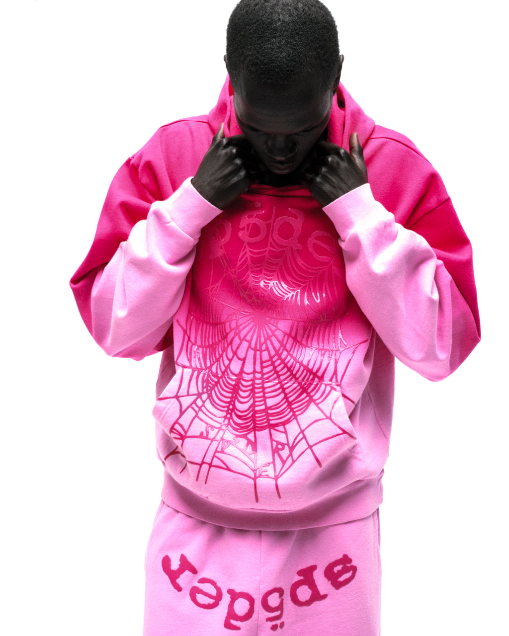 Man in pink ombre OG Web hoodie with spiderweb graphic and matching sweatpants.