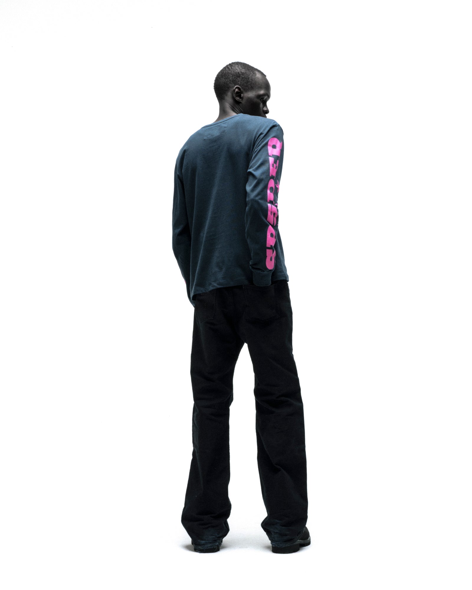 Dark-skinned man in a navy MX555 cotton long sleeve tee with pink graphic print on the right sleeve.