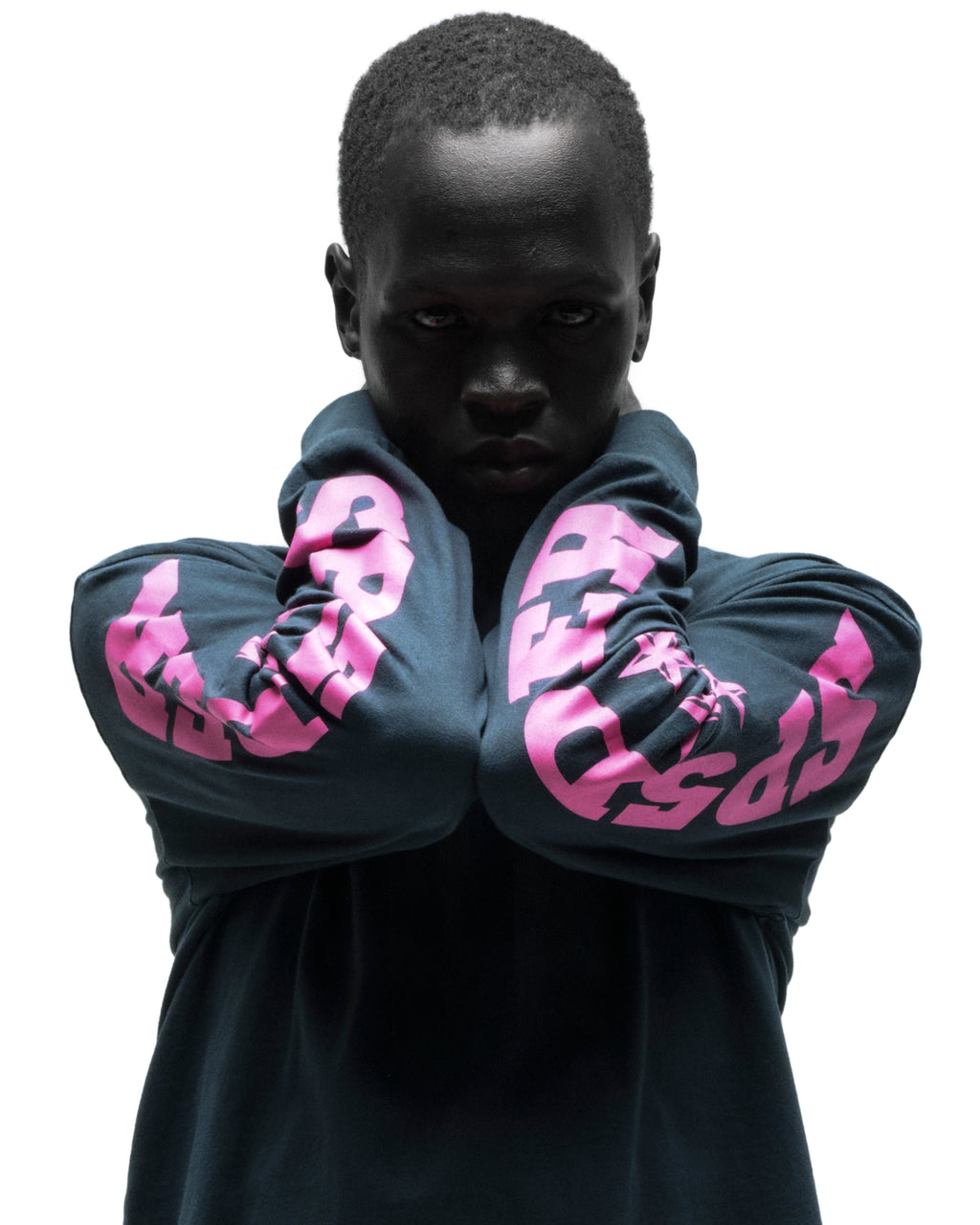 Dark-skinned model in a black cotton MX555 long sleeve tee with bold pink graphic print on sleeves.