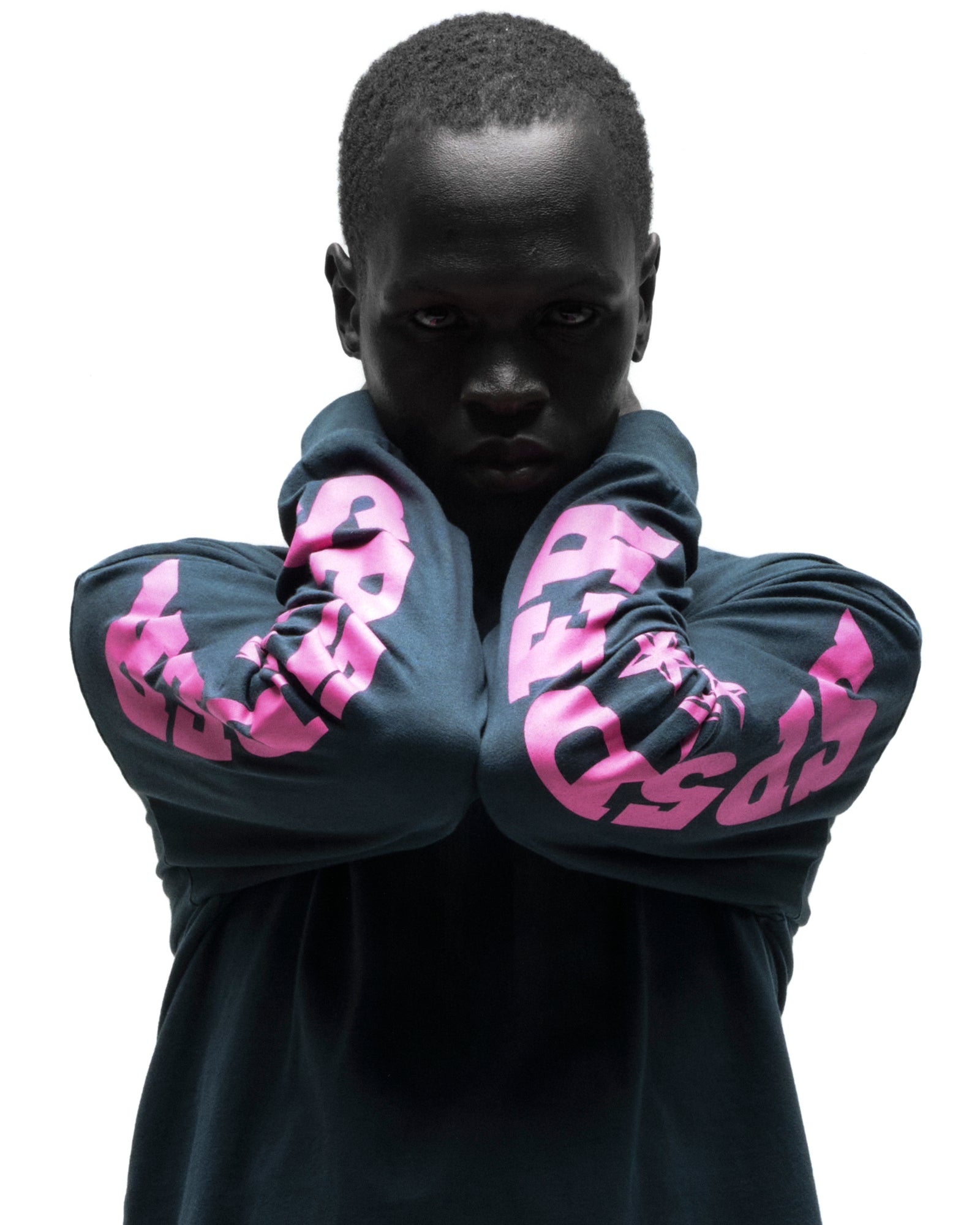 Dark-skinned model in a black cotton MX555 long sleeve tee with bold pink graphic print on sleeves.