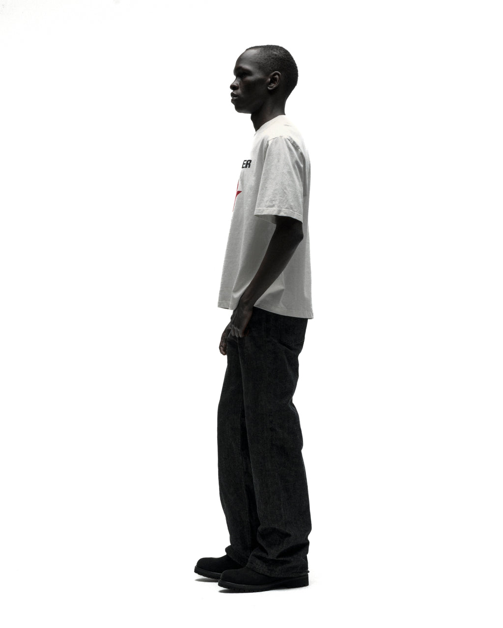 Man in white cotton FIVE POINT TEE with graphic print, black jeans, and shoes.
