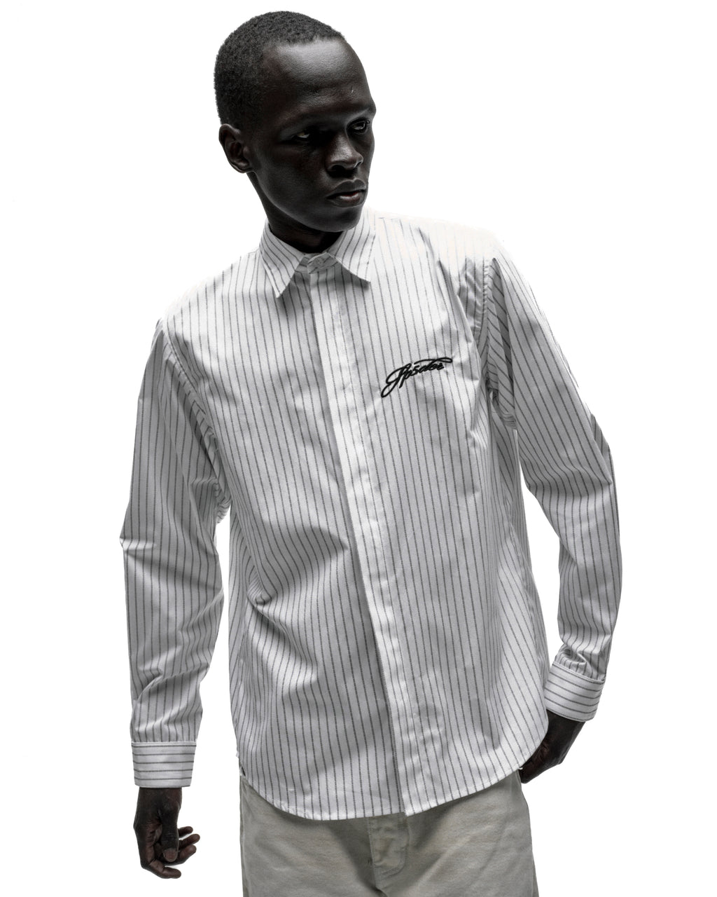 White woven cotton button-down shirt with thin black pinstripes, spread collar, and embroidered script logo.