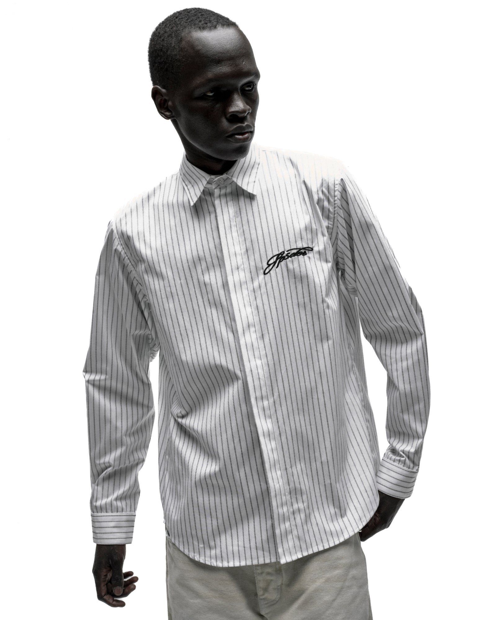 White woven cotton button-down shirt with thin black pinstripes, spread collar, and embroidered script logo.