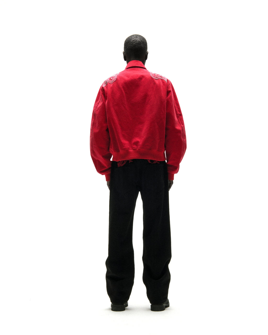 Red cotton canvas bomber jacket with studded shoulders and embroidered script, viewed from the back.