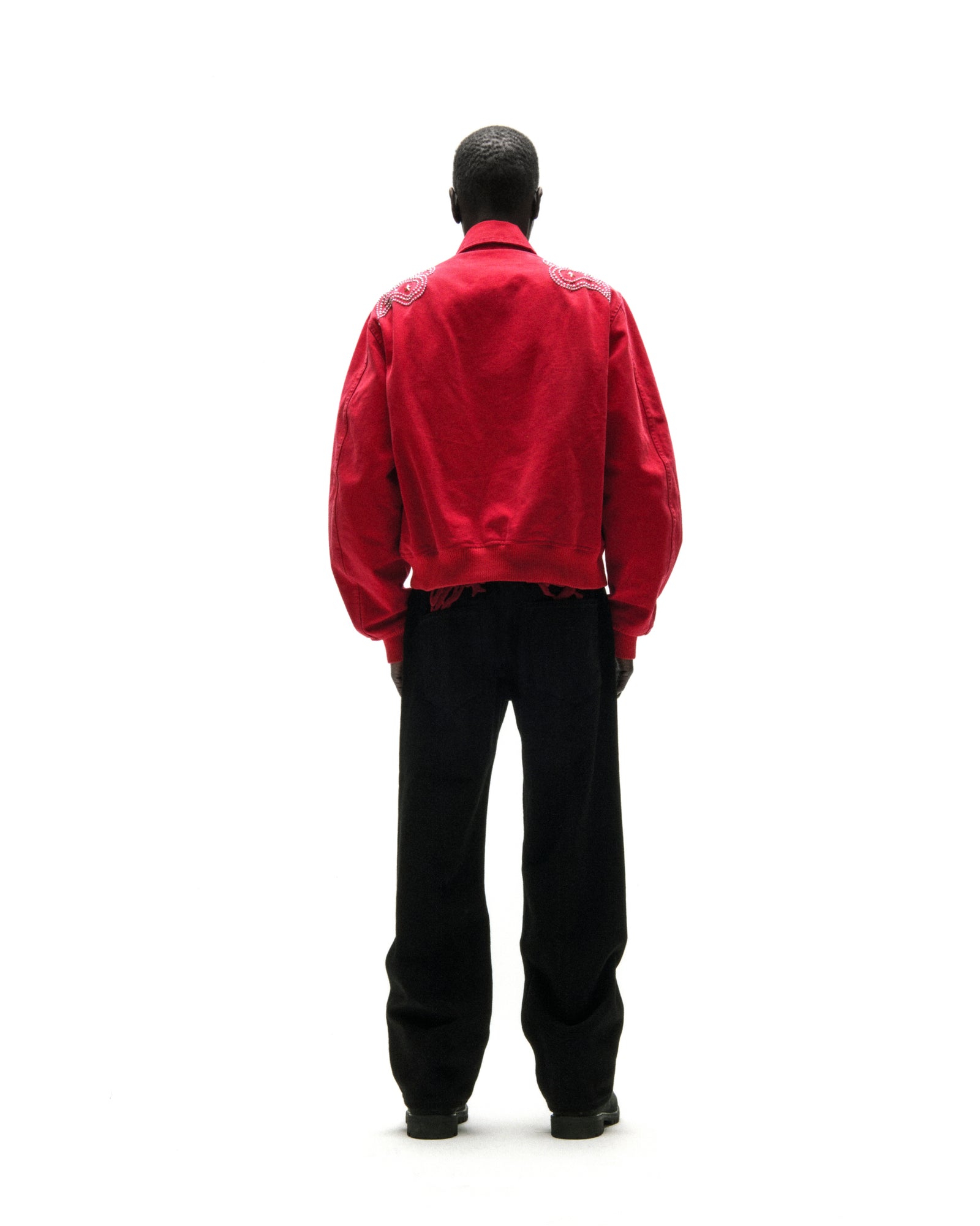 Red cotton canvas bomber jacket with studded shoulders and embroidered script, viewed from the back.