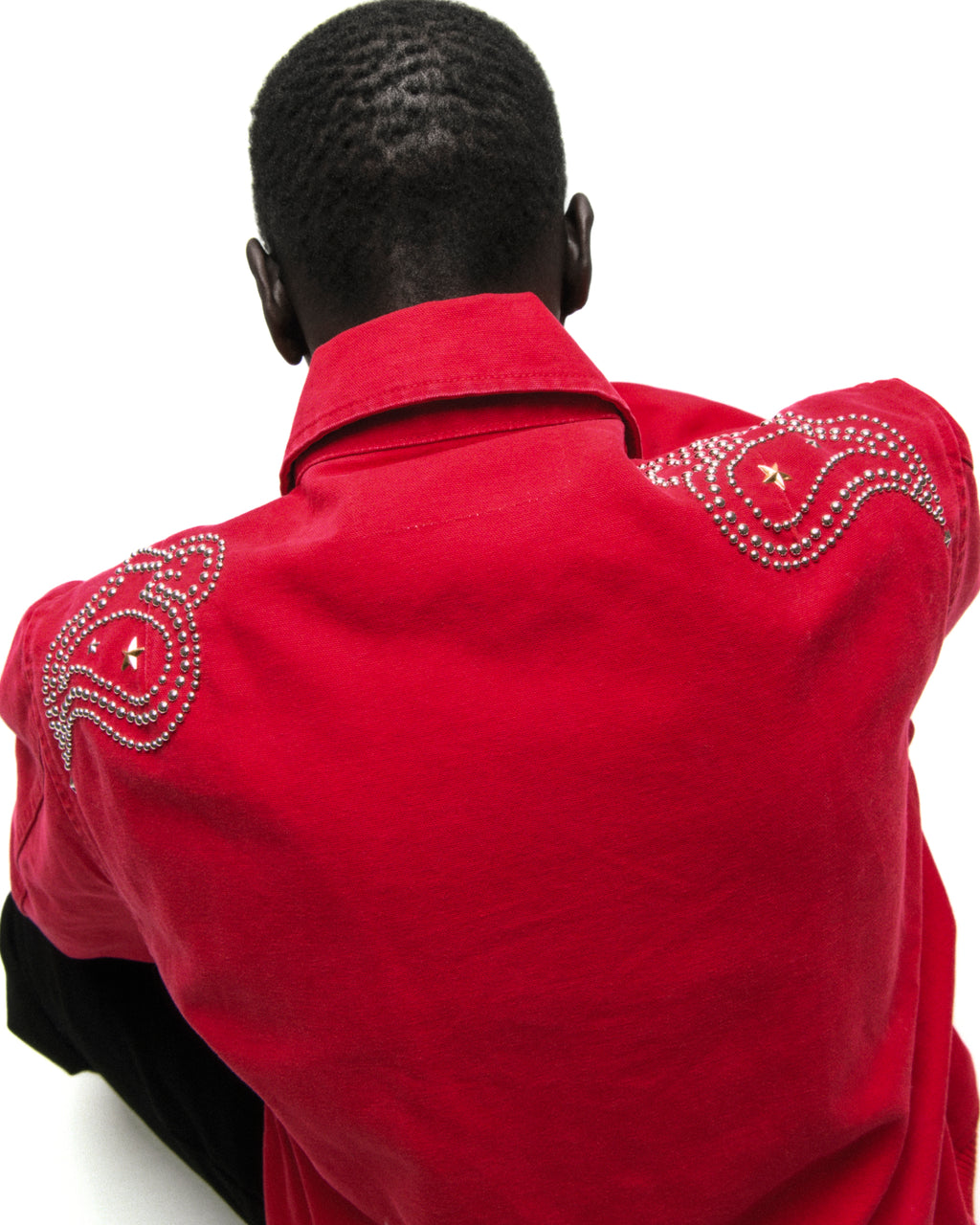 Back of a red cotton canvas bomber jacket with studded shoulder detailing.