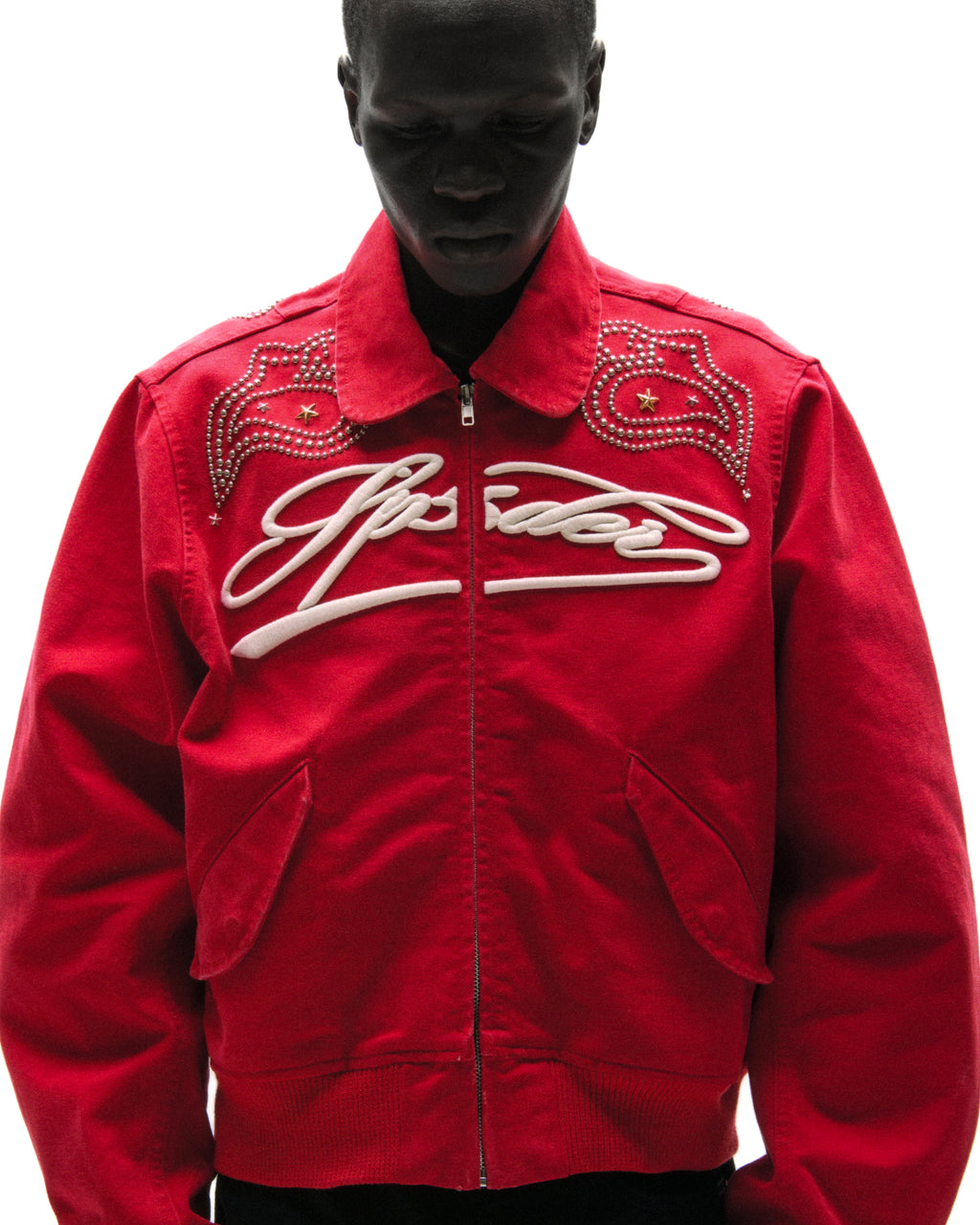 Red cotton canvas bomber jacket with white embroidered script and studded shoulder detailing.