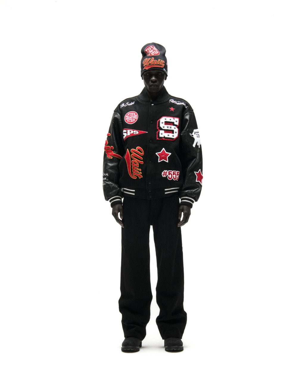 Black wool varsity jacket with leather sleeves, debossed web design, and multiple embroidered patches.