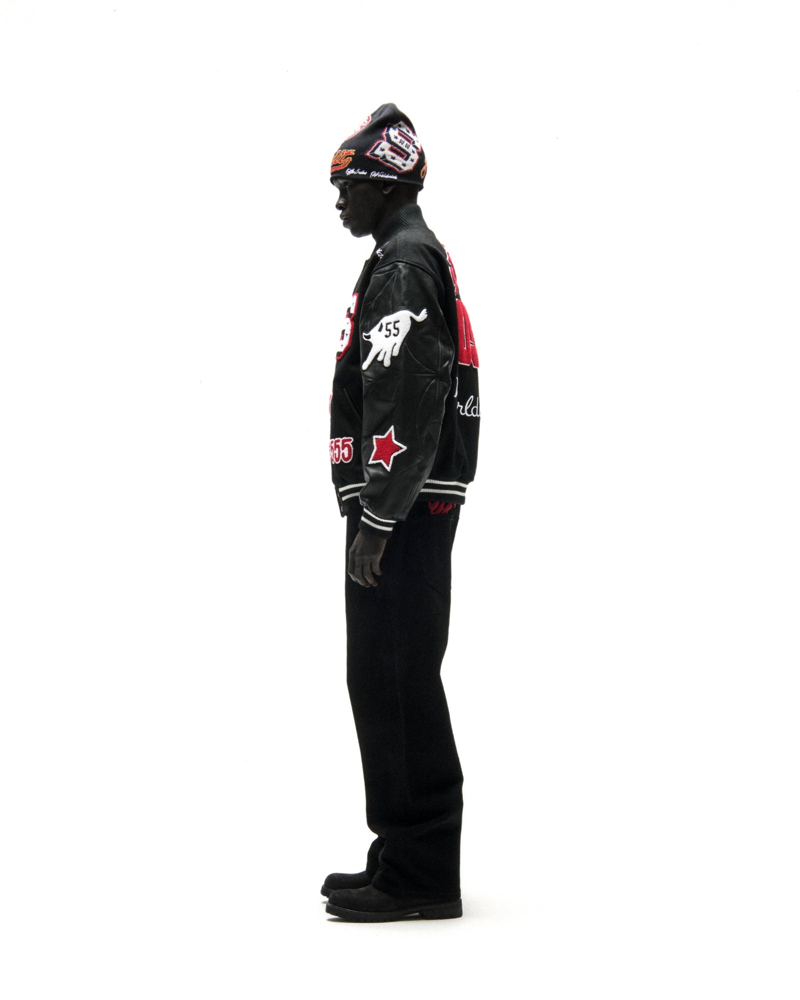 Black wool varsity jacket with leather sleeves, debossed web design, and embroidered patches.