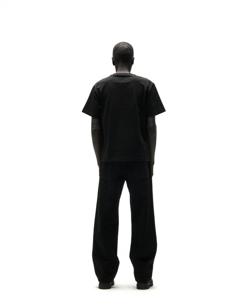 Back view of a person wearing a black cotton t-shirt and black pants.