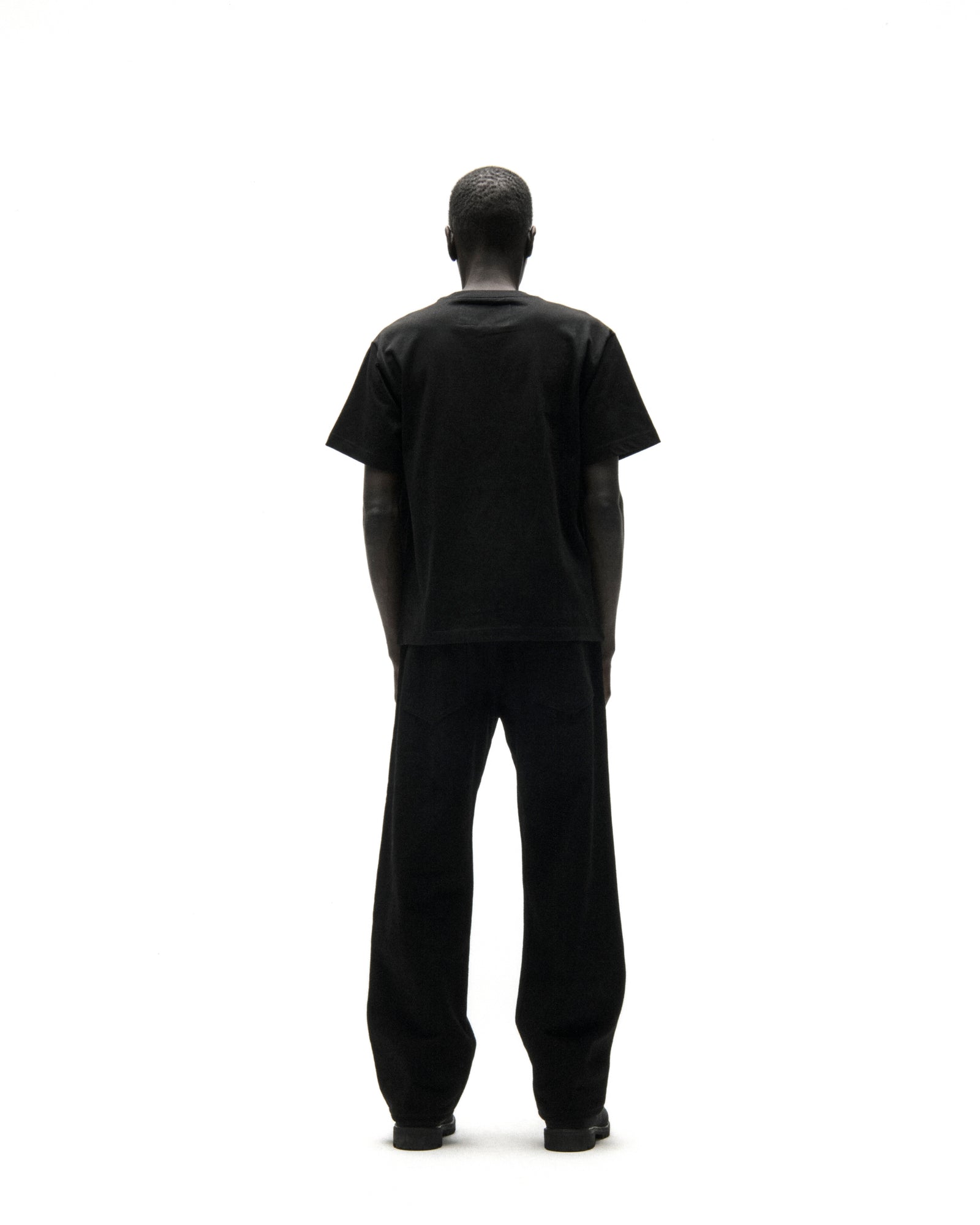 Back view of a person wearing a black cotton t-shirt and black pants.