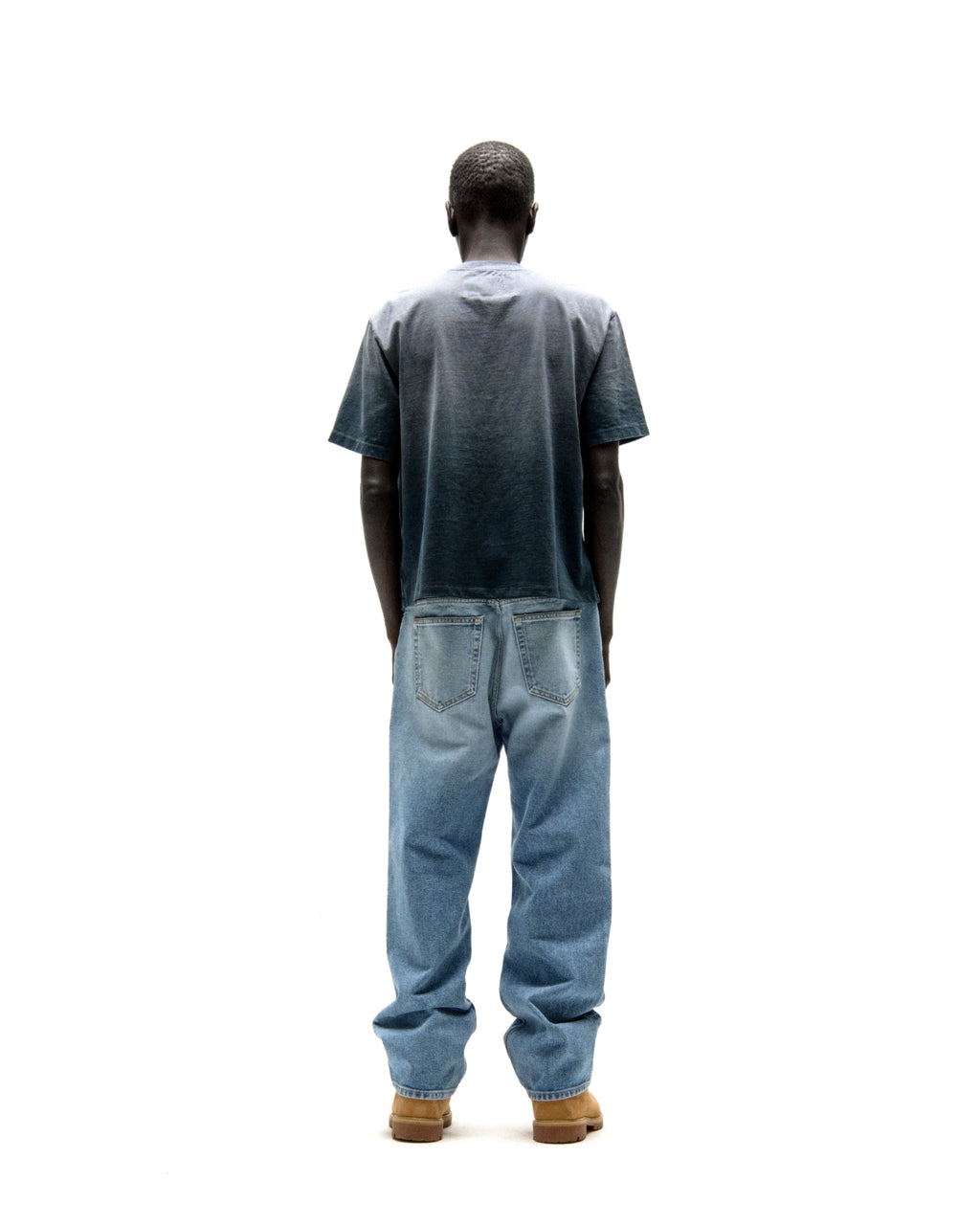 Man from behind wearing a faded wash cotton tee and light blue jeans.