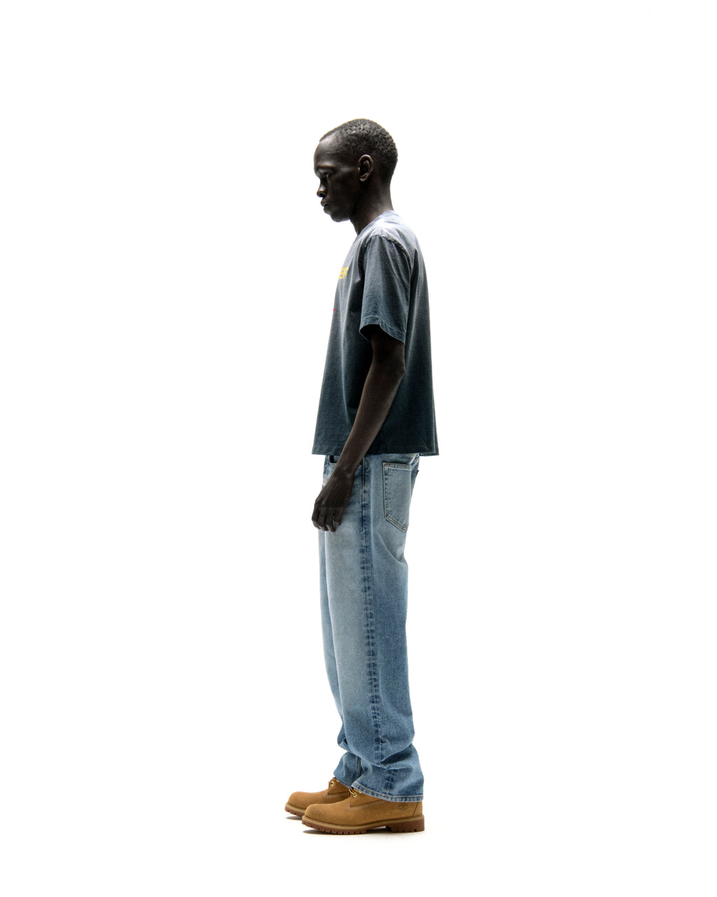 Man in a faded wash, standard fit, 100% cotton FIVE POINT TEE with a graphic print, paired with jeans.