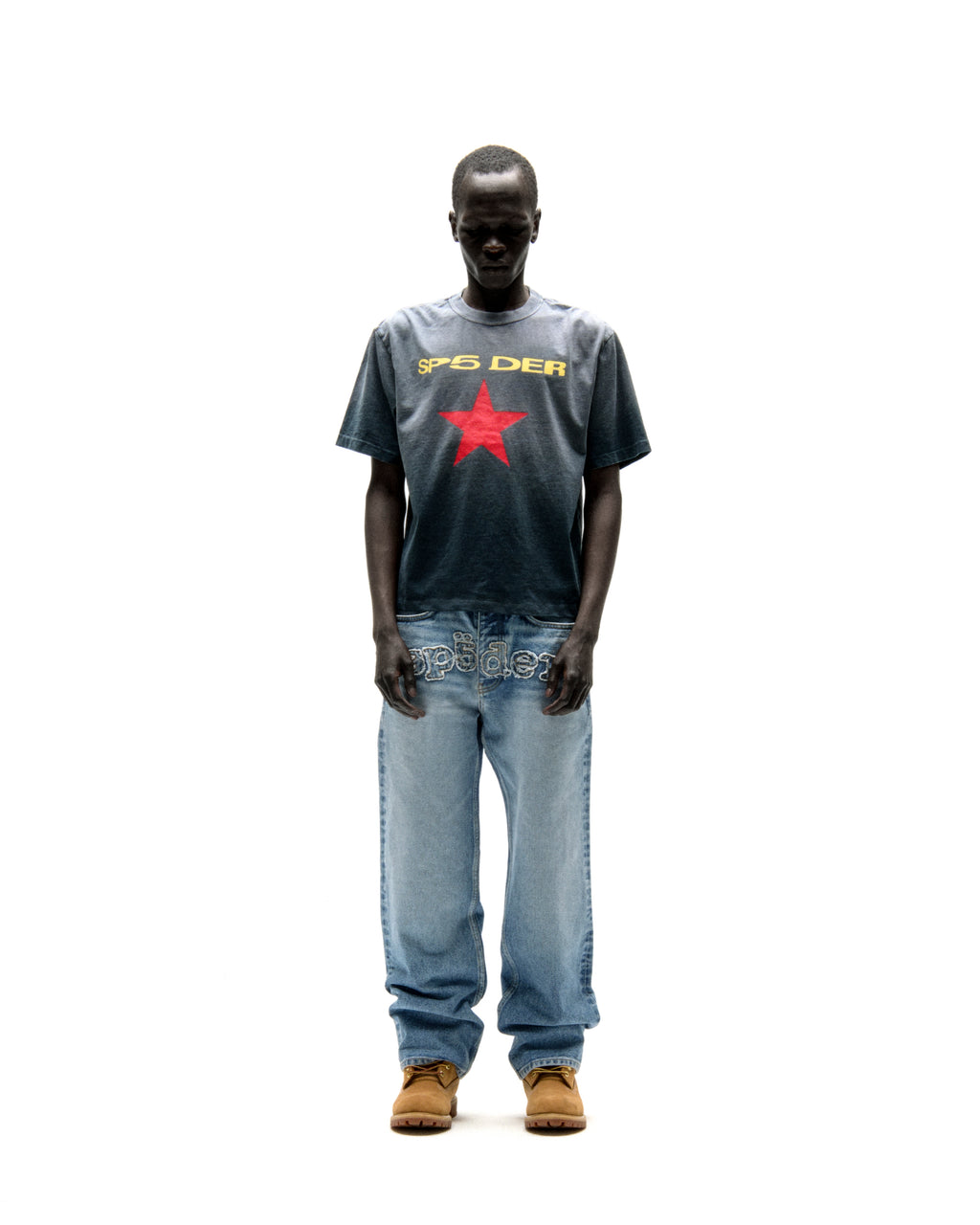 Faded wash cotton tee with "SP5DER" text and a red star graphic, worn with light wash jeans.