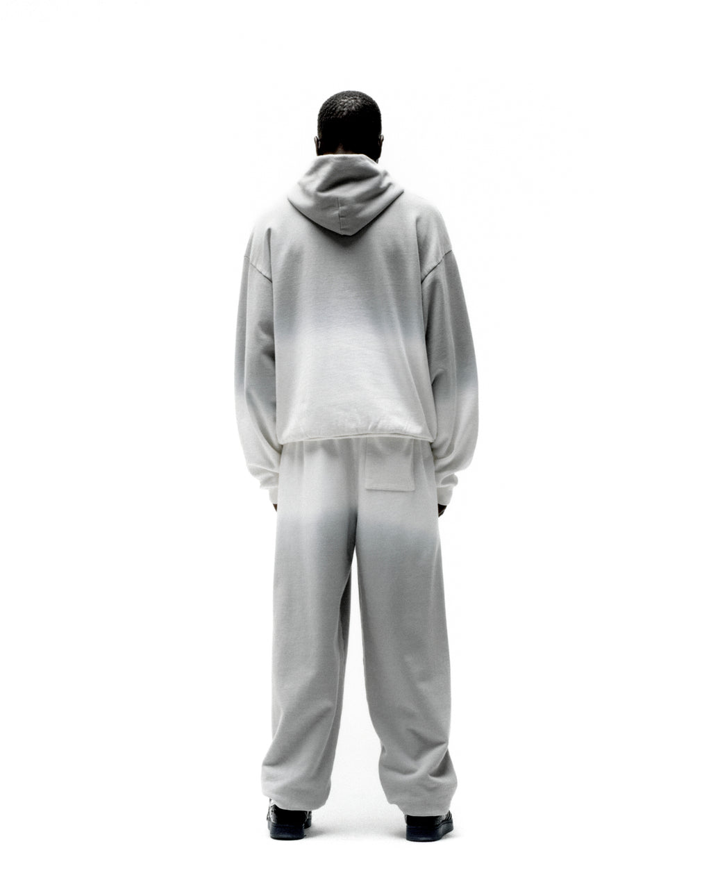 Back view of a person wearing a gray and white ombre fleece hoodie and matching sweatpants.