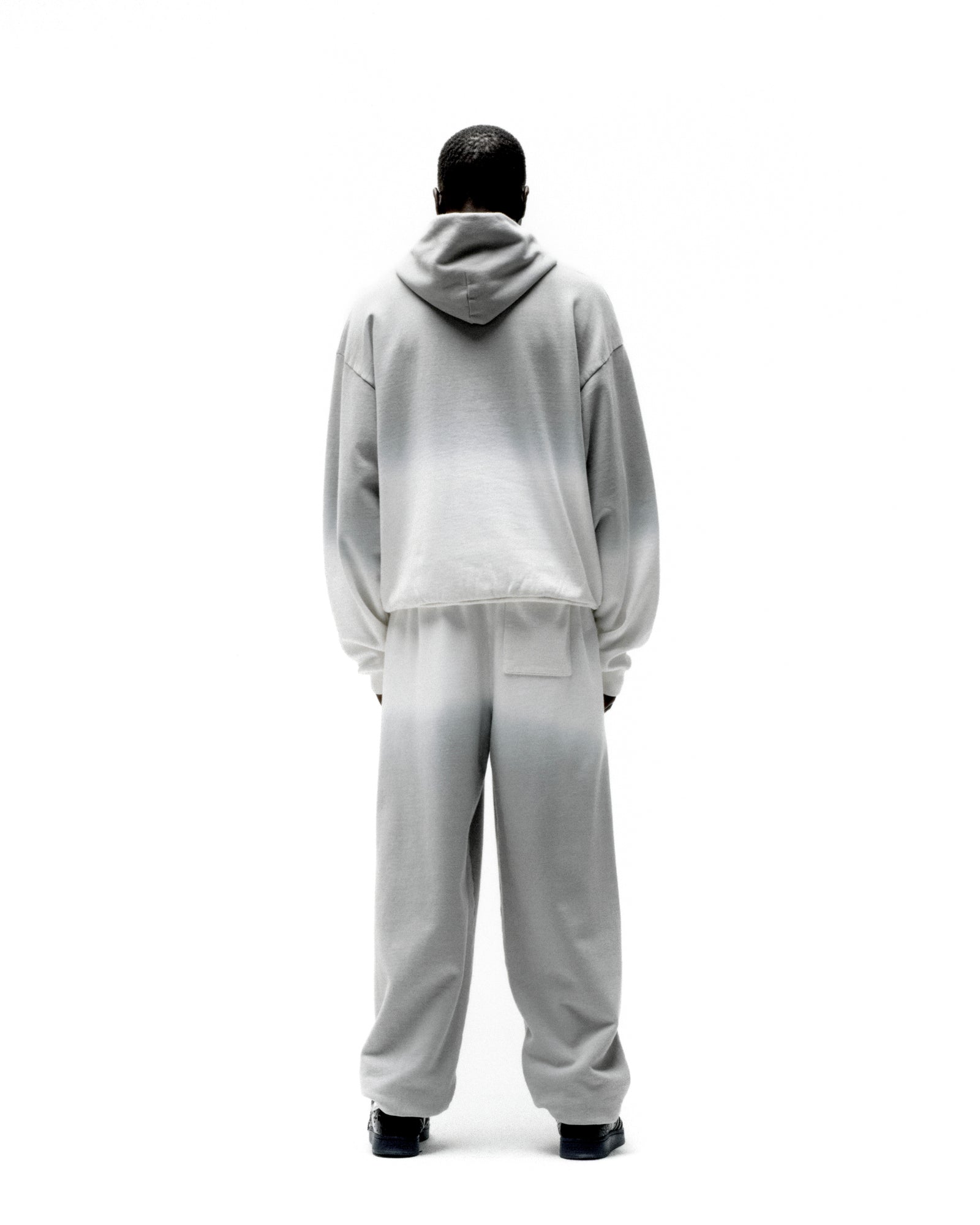Back view of a person wearing a gray and white ombre fleece hoodie and matching sweatpants.