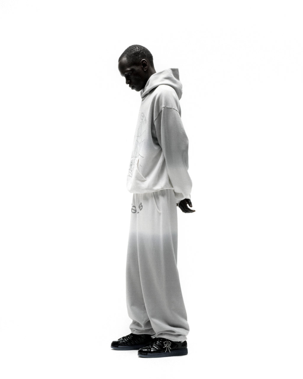 Man in an OG Web Ombre Hoodie and sweatpants, featuring a light grey gradient and puff print.