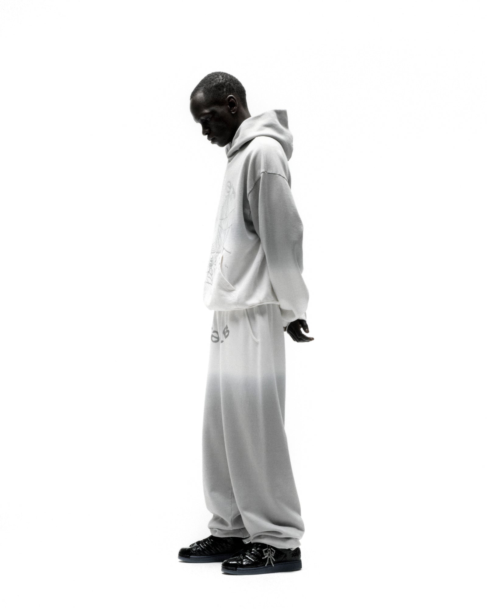 Man in an OG Web Ombre Hoodie and sweatpants, featuring a light grey gradient and puff print.
