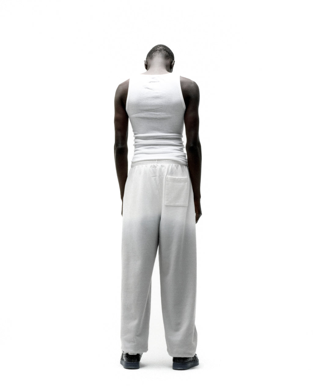 Back view of a person wearing white OG WEB OMBRE SWEATPANTS with elasticized waistband and cuffs.