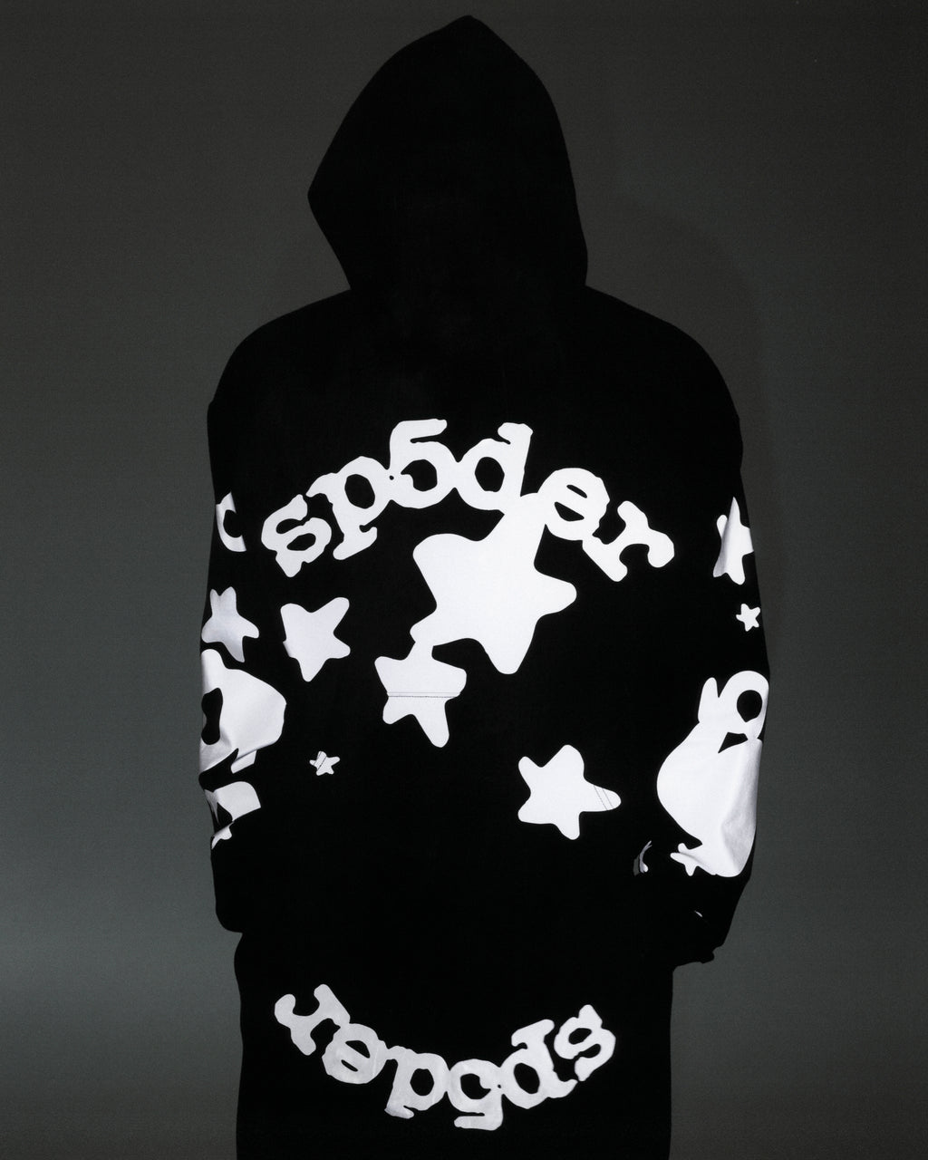 Black cotton fleece hoodie with reflective 'SP5DER' text and star print on back and sleeves.