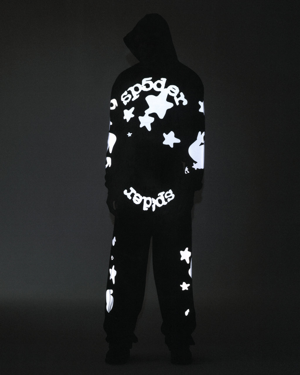 Black cotton fleece hoodie and sweatpants with reflective 'SP5DER' text and star prints.