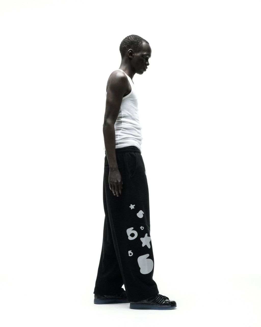 Black wide-leg cotton fleece sweatpants with reflective 'SP5DER' text, '5' and star designs.