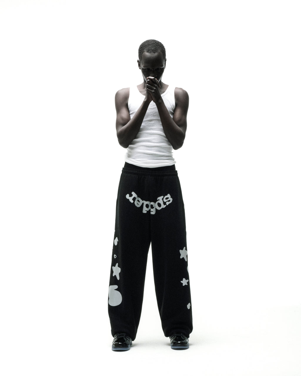Black wide-leg sweatpants with reflective "SP5DER" text, "5", and star designs.