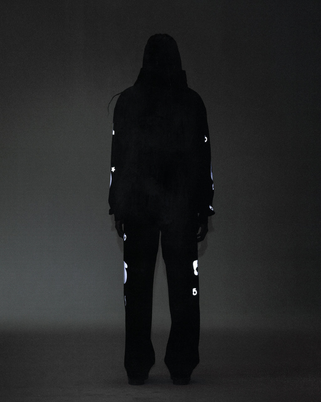 Person in black REFLECTIVE BELUGA SWEATPANT and hoodie, showing reflective 3M print, 'SP5DER' text, '5' and star design.