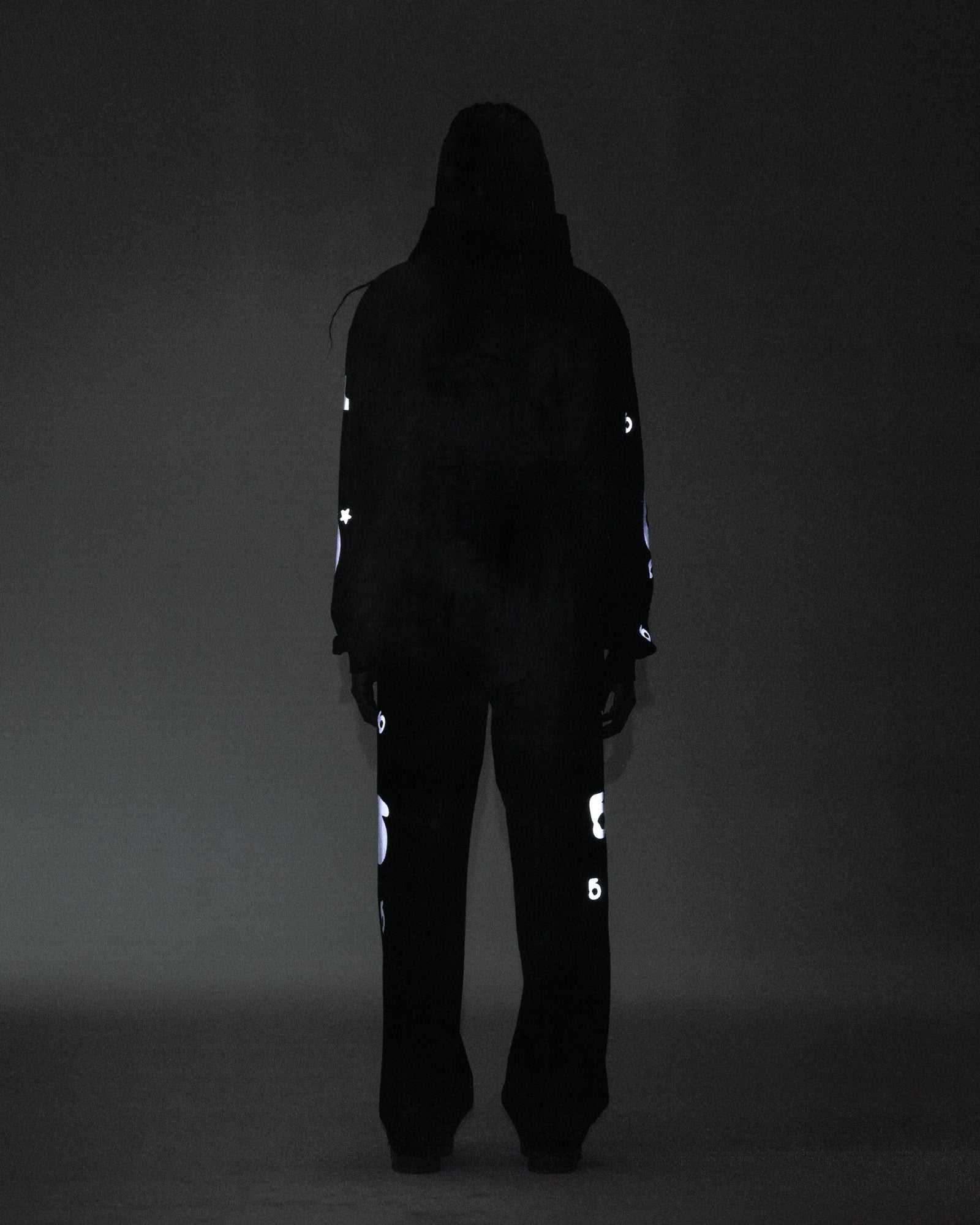 Person in black REFLECTIVE BELUGA SWEATPANT and hoodie, showing reflective 3M print, 'SP5DER' text, '5' and star design.