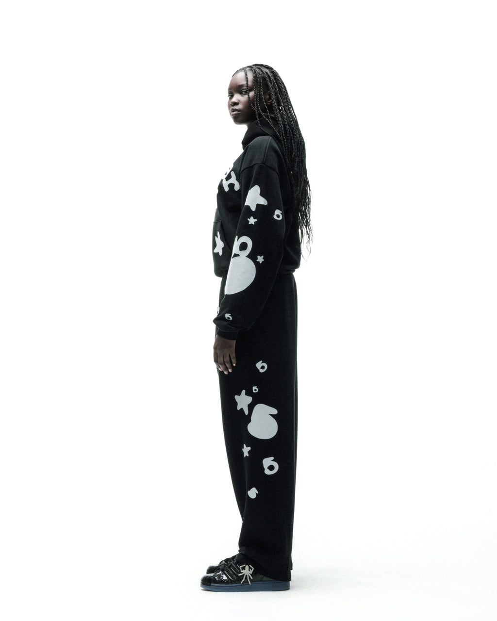 Model wearing black REFLECTIVE BELUGA SWEATPANTS with white 'SP5DER' text, '5' and star designs.