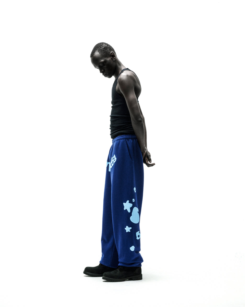 Model wearing blue Beluga V2 sweatpants with light blue puff print stars, '5', and 'SP5DER' text.