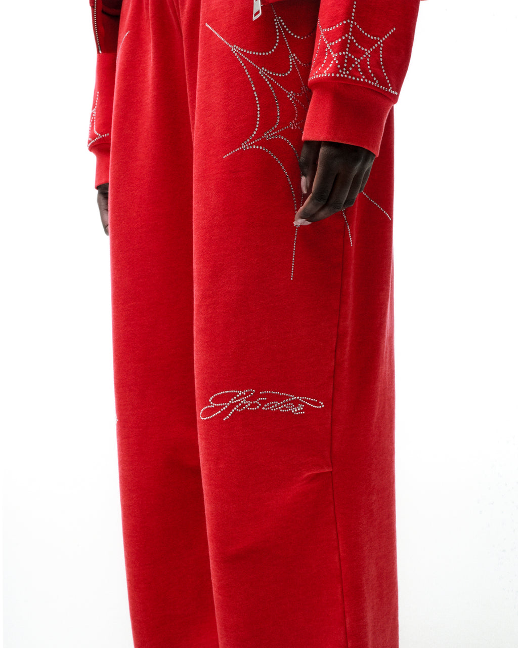 Red cotton fleece sweatpants with rhinestone spider web and text details.