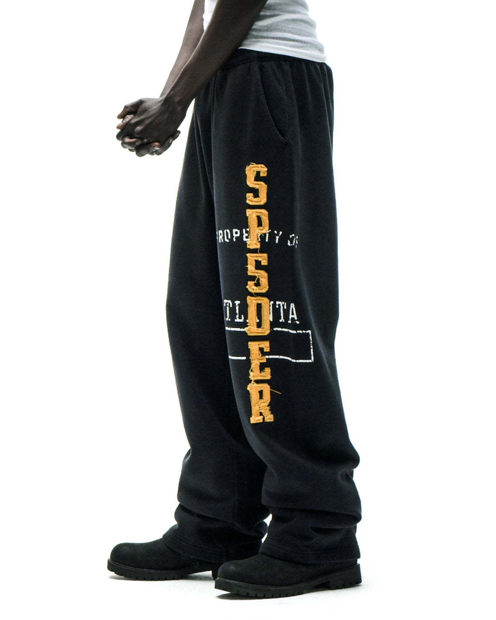 Black cotton fleece sweatpants with raised chenille-style "SP5DER" lettering and faded graphic print.