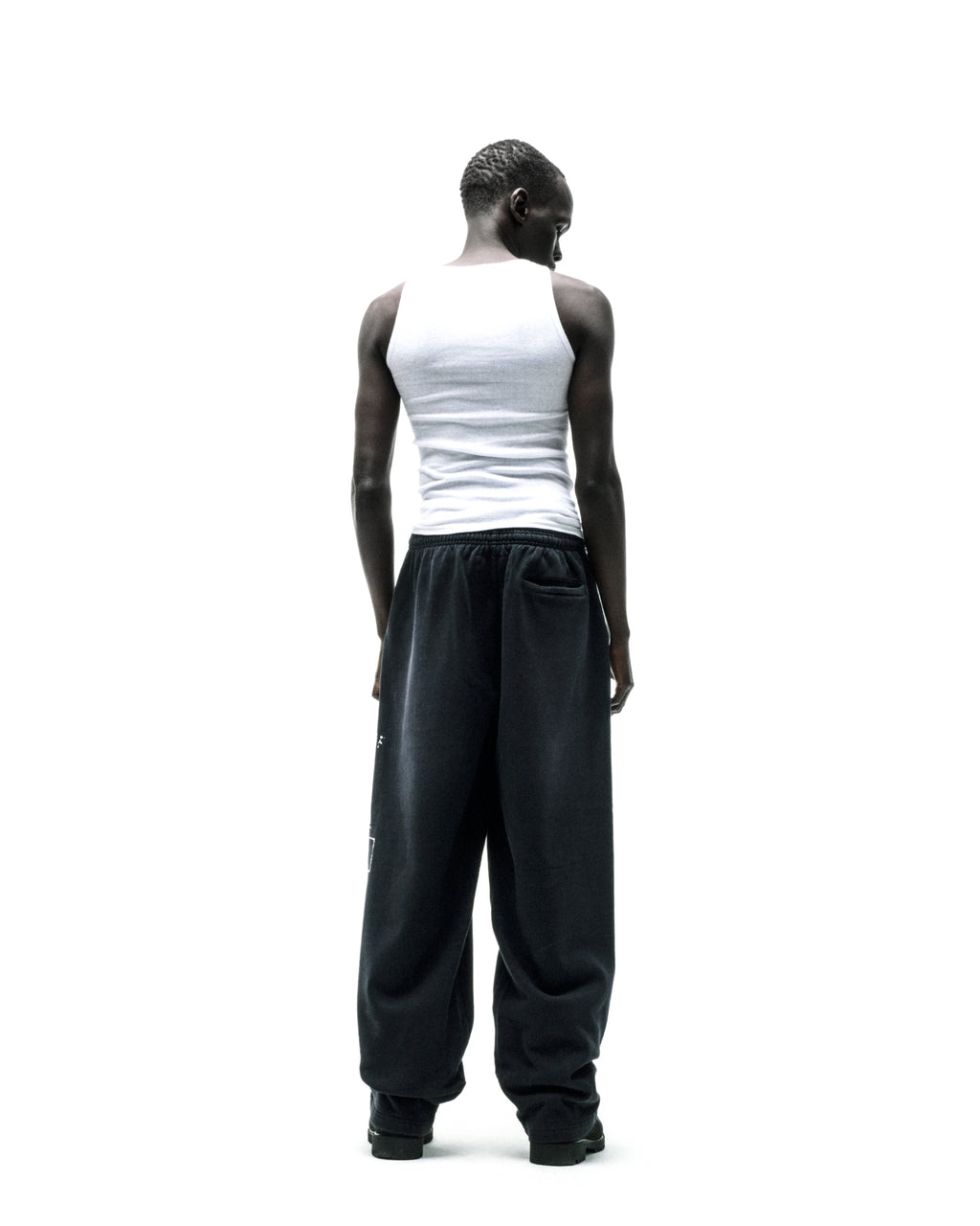 Black wide-leg fleece sweatpants with faded graphic print and raised chenille lettering.