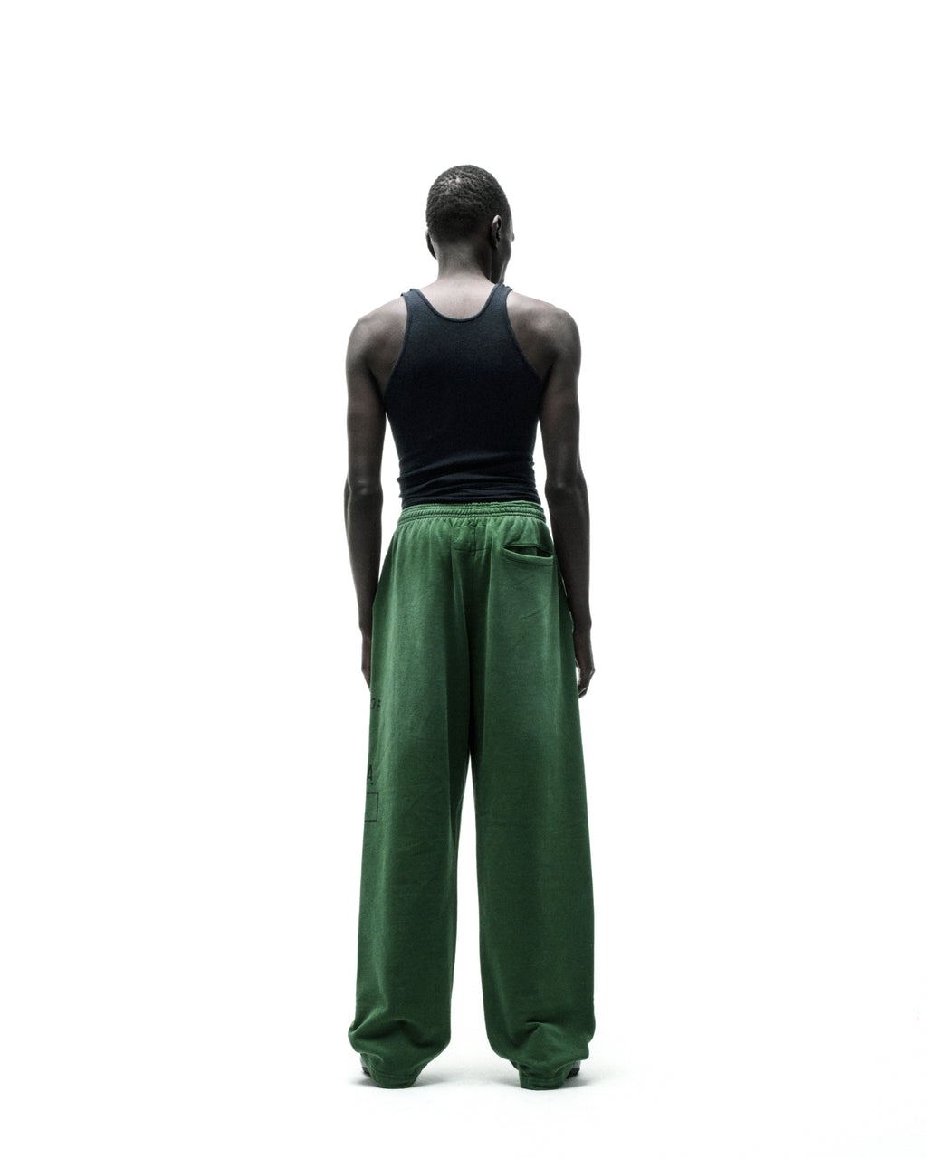 Model from behind wearing wide-leg green fleece sweatpants with elastic waistband.