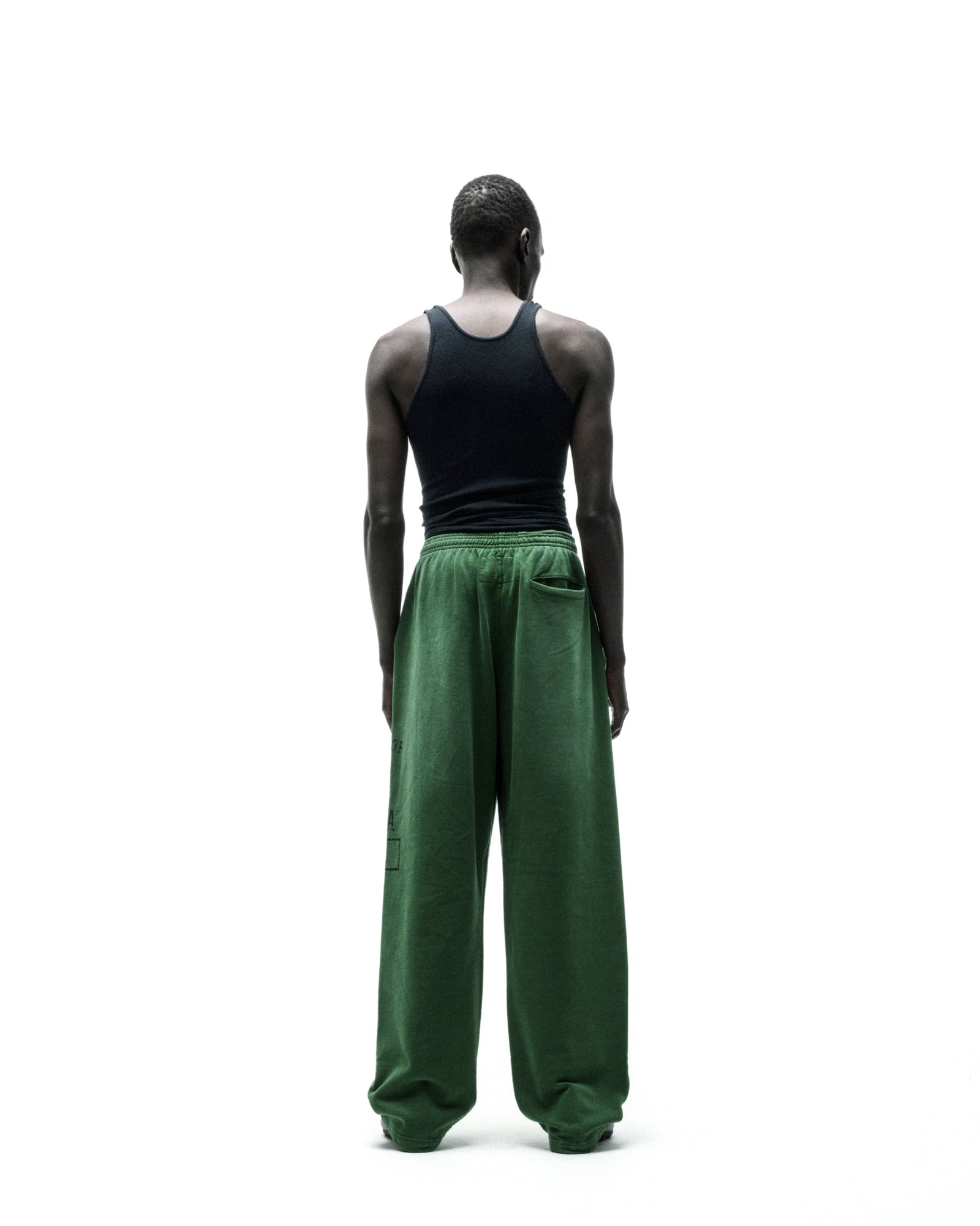 Model from behind wearing wide-leg green fleece sweatpants with elastic waistband.