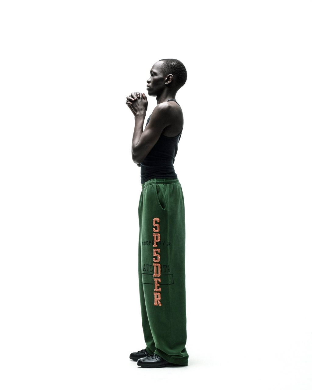 Model in green ISSUE 404 wide-leg sweatpants with raised, frayed "SPSDER" lettering and faded graphic.