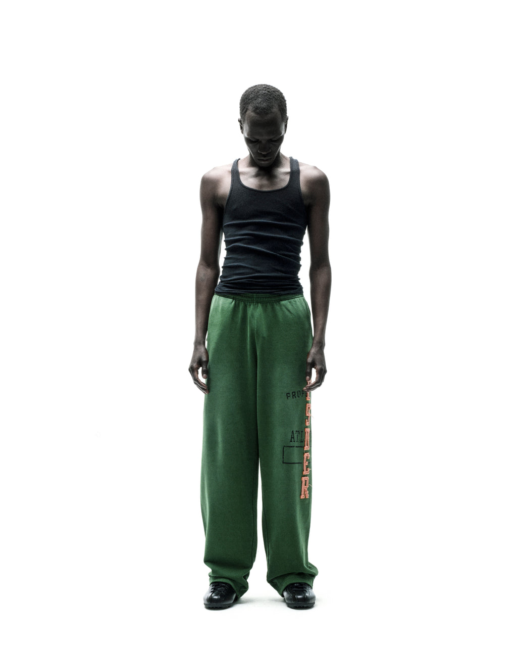 Model wearing ISSUE 404 green cotton fleece sweatpants with faded graphic print and wide-leg silhouette.